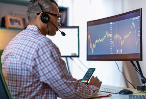 Focused man with headphones at desk, utilizing expert advisory services for tailored FX risk mitigation and strategic hedging solutions