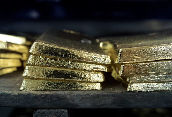 A stack of gold bars neatly arranged on a table, gleaming with a lustrous shine, symbolizing the PMXecute platform for real-time precious metals and foreign exchange pricing