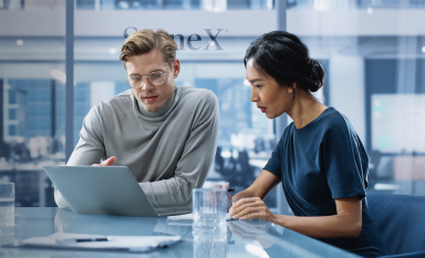 Finance professionals collaborating on a laptop, engaging in financial trading on the StoneX platform