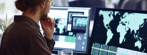 A man studies a world map on a computer screen, exploring StoneX's broad market coverage in securities