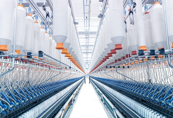 High-tech cotton spinning facility with rows of yarn spools, representing sustainable and ethical cotton sourcing.