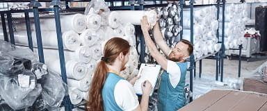 Workers handling rolls of cotton fabric in a textile mill, ensuring a stable cotton supply chain.