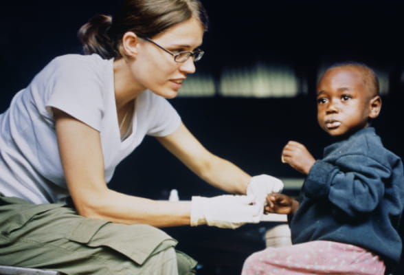 Volunteer helping a child, symbolizing StoneX's partnership with Save the Children.