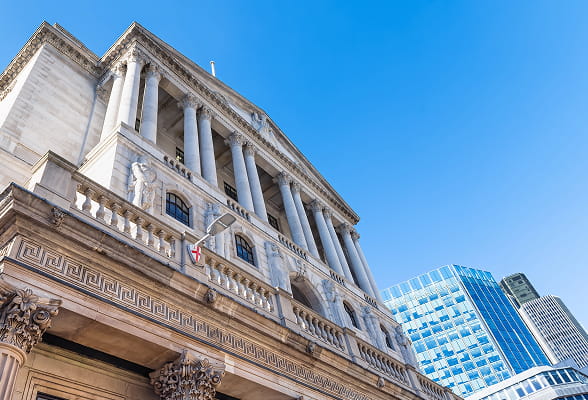 Low-angle view of a classical bank building alongside modern skyscrapers, symbolizing the blend of tradition and innovation in StoneX’s SWIFT compliance services, including CSP assessments, gpi, ISO 20022 migration, and payment confirmations.
