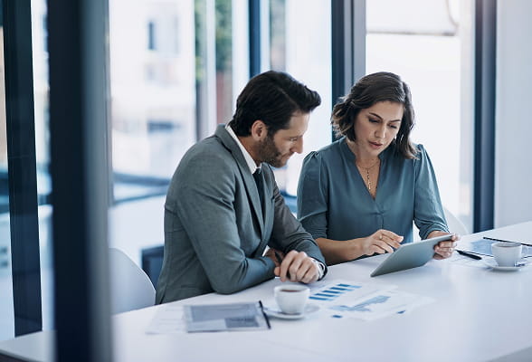 Financial professionals reviewing digital asset research on a tablet, representing StoneX Digital’s market analysis solutions.