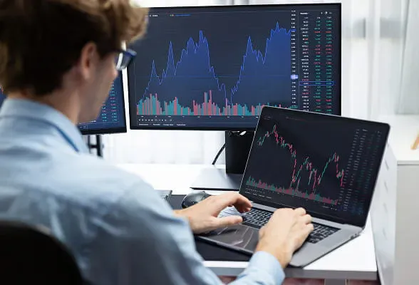 Institutional trader analyzing digital asset markets on multiple screens, representing StoneX Digital’s liquidity and trading solutions.