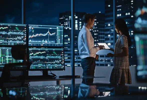 Traders reviewing data on multiple screens, representing institutional liquidity and FX risk management for hedge funds and asset managers.