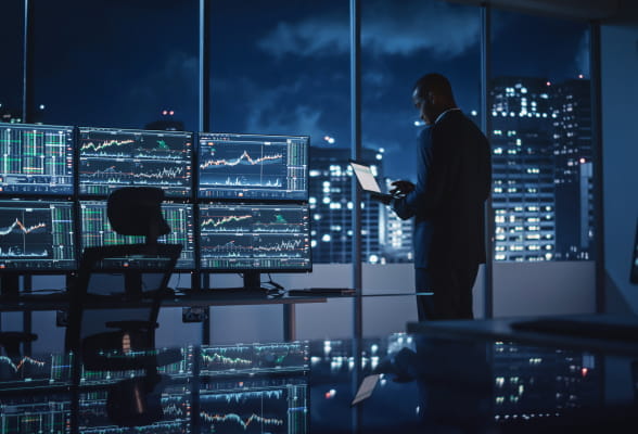 Professional reviewing financial data on multiple screens, representing institutional liquidity and FX solutions for money service businesses.