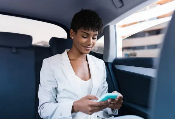 Professional using a smartphone in a car, highlighting StoneX Wealth Management's advanced platforms and technology for efficient account management