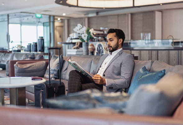 Man reading in a lounge, highlighting StoneX Wealth Management's personalized financial services for international private clients