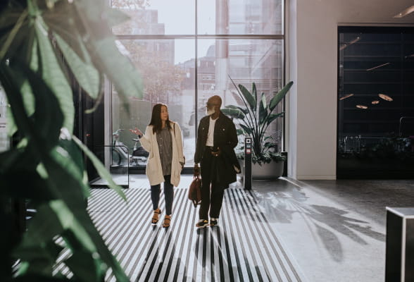 Two professionals walking in an office building, highlighting StoneX Wealth Management's Practice Solutions Group for growing and managing practices